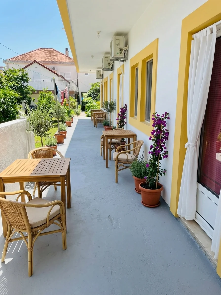 Terrace with wicker chairs, wooden tables and potted plants alongside the apartments